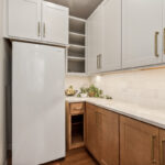 Light brown stained kitchen cabinets and white painted accent cabinets with glass door inserts.