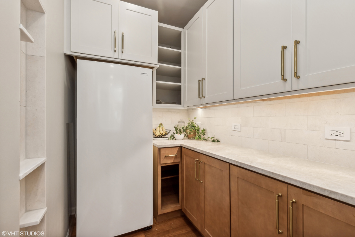Light brown stained kitchen cabinets and white painted accent cabinets with glass door inserts.