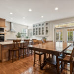 Light brown stained kitchen cabinets and white painted accent cabinets with glass door inserts.