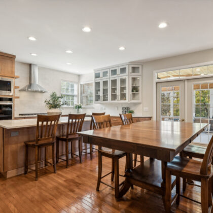 Light brown stained kitchen cabinets and white painted accent cabinets with glass door inserts.