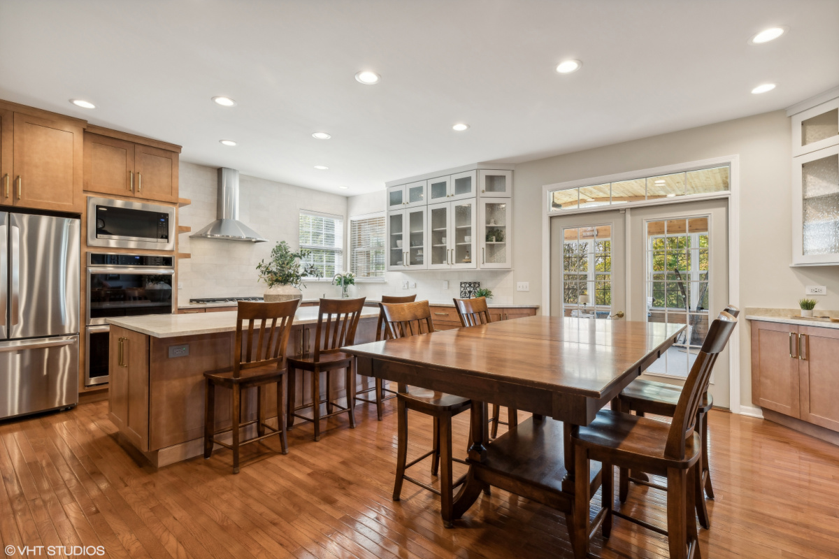 Light brown stained kitchen cabinets and white painted accent cabinets with glass door inserts.