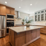 Light brown stained kitchen cabinets and white painted accent cabinets with glass door inserts.
