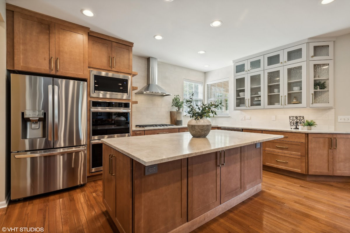 Light brown stained kitchen cabinets and white painted accent cabinets with glass door inserts.