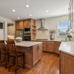 Light brown stained kitchen cabinets and white painted accent cabinets with glass door inserts.