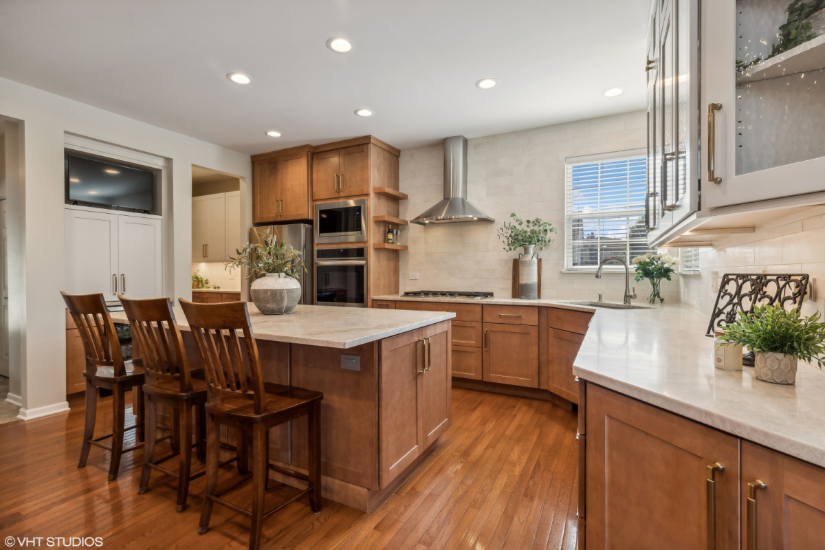 Light brown stained kitchen cabinets and white painted accent cabinets with glass door inserts.