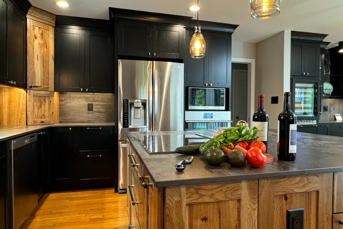 Kitchen with black painted and rustic natural cabinets showing stainless steel appliances