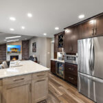 Kitchen cabinets stained in light Montana and rich Espresso stains on maple. View includes a large stainless steel fridge.