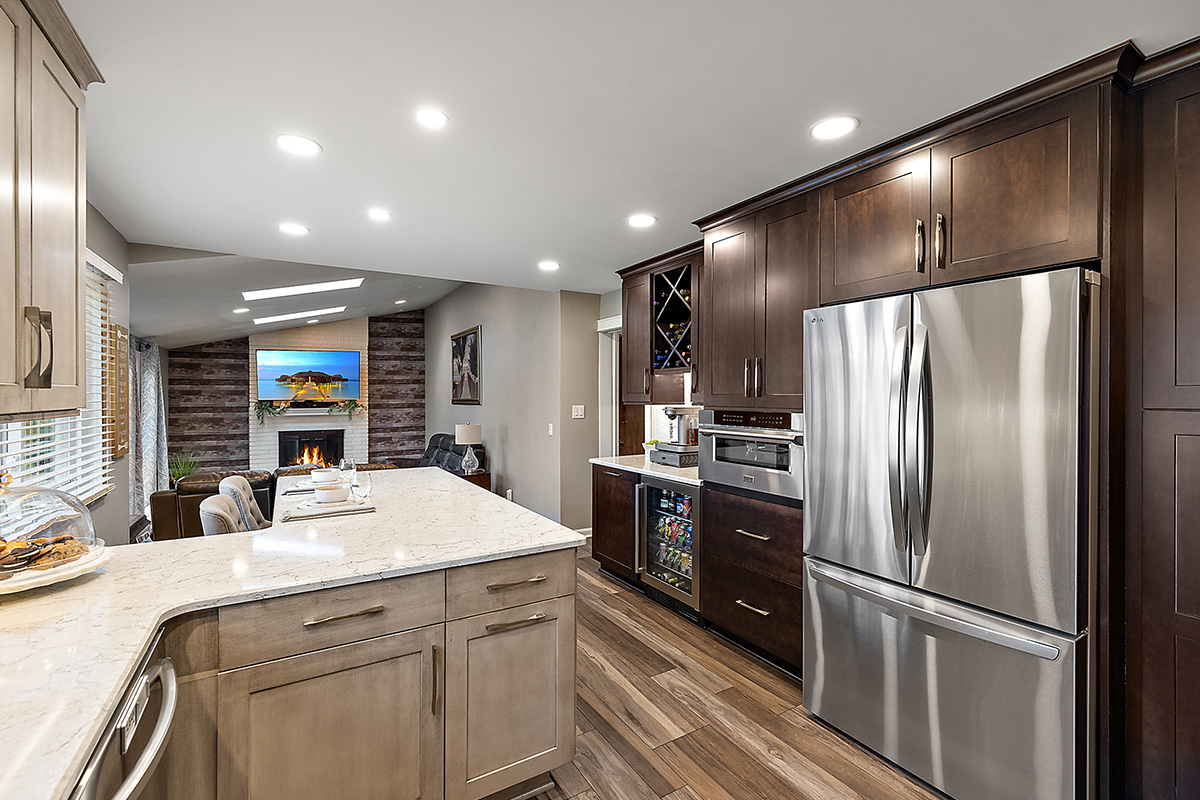 Kitchen cabinets stained in light Montana and rich Espresso stains on maple. View includes a large stainless steel fridge.