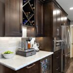 Coffee bar area in rich Espress stain. Includes a view of a countertop coffee machine and wine rack above.