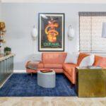 Living room space with painted green cabinets below a tv on the wall and stained white oak book cases to the left framed with green end panels.