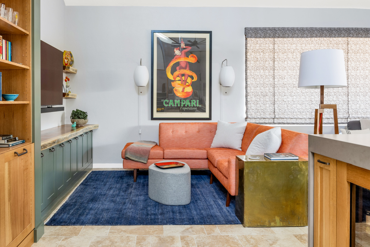 Living room space with painted green cabinets below a tv on the wall and stained white oak book cases to the left framed with green end panels.