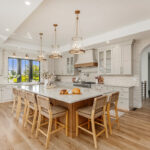 Painted and stained kitchen cabinets in a large open space with large windows.