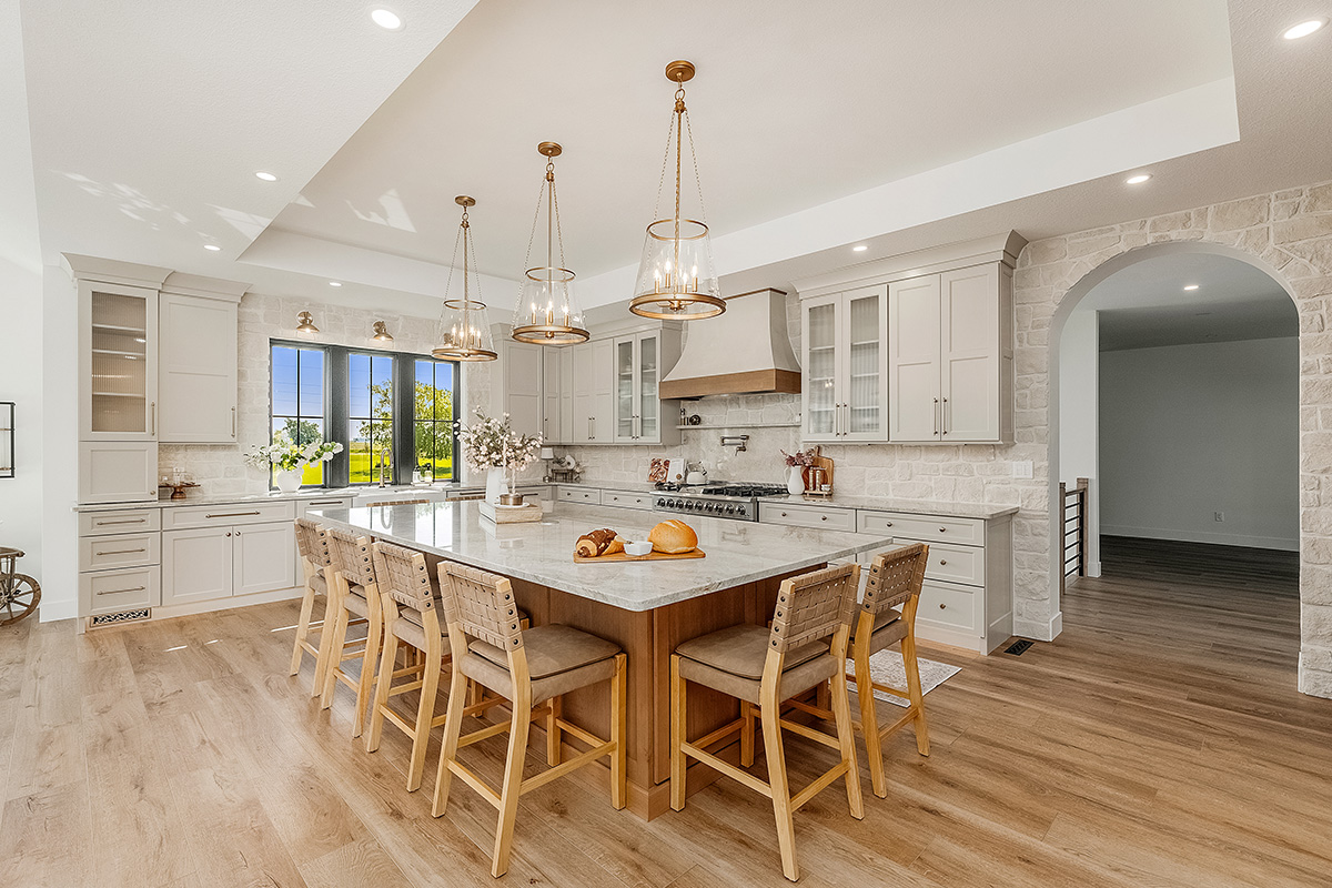 Painted and stained kitchen cabinets in a large open space with large windows.