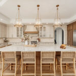 Painted and stained kitchen cabinets in a large open space with large windows.