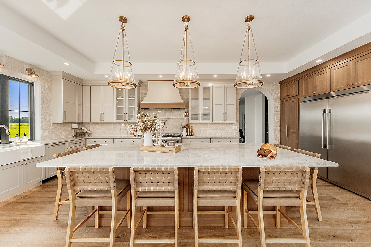Painted and stained kitchen cabinets in a large open space with large windows.