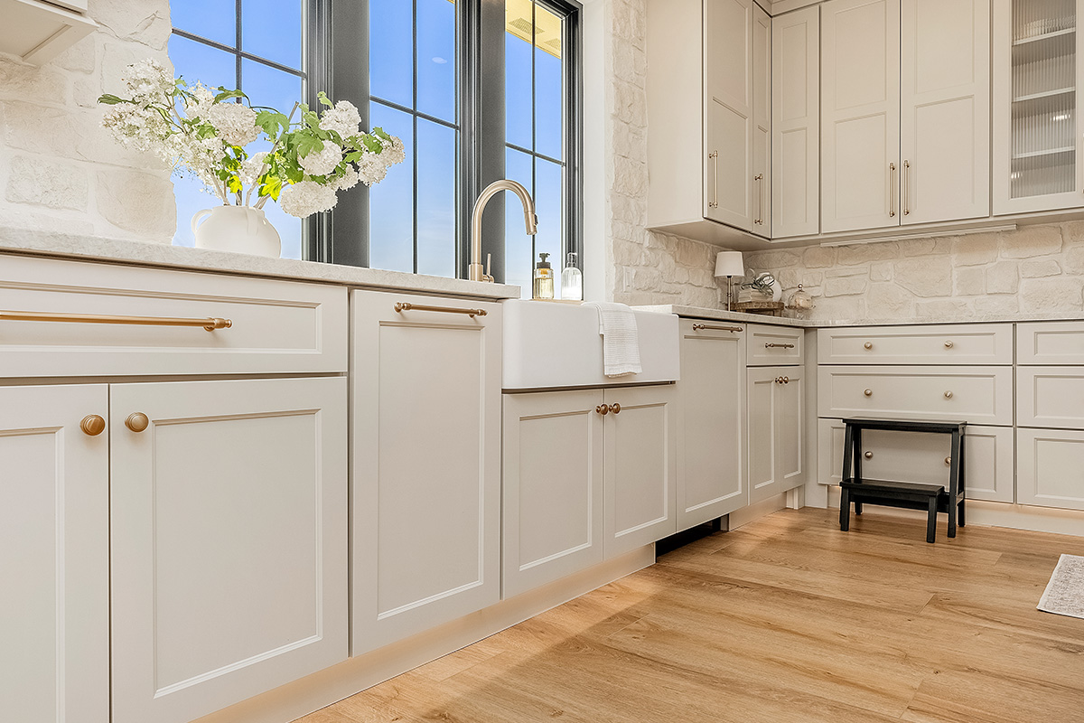 Painted and stained kitchen cabinets in a large open space with large windows.