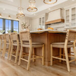 Painted and stained kitchen cabinets in a large open space with large windows.