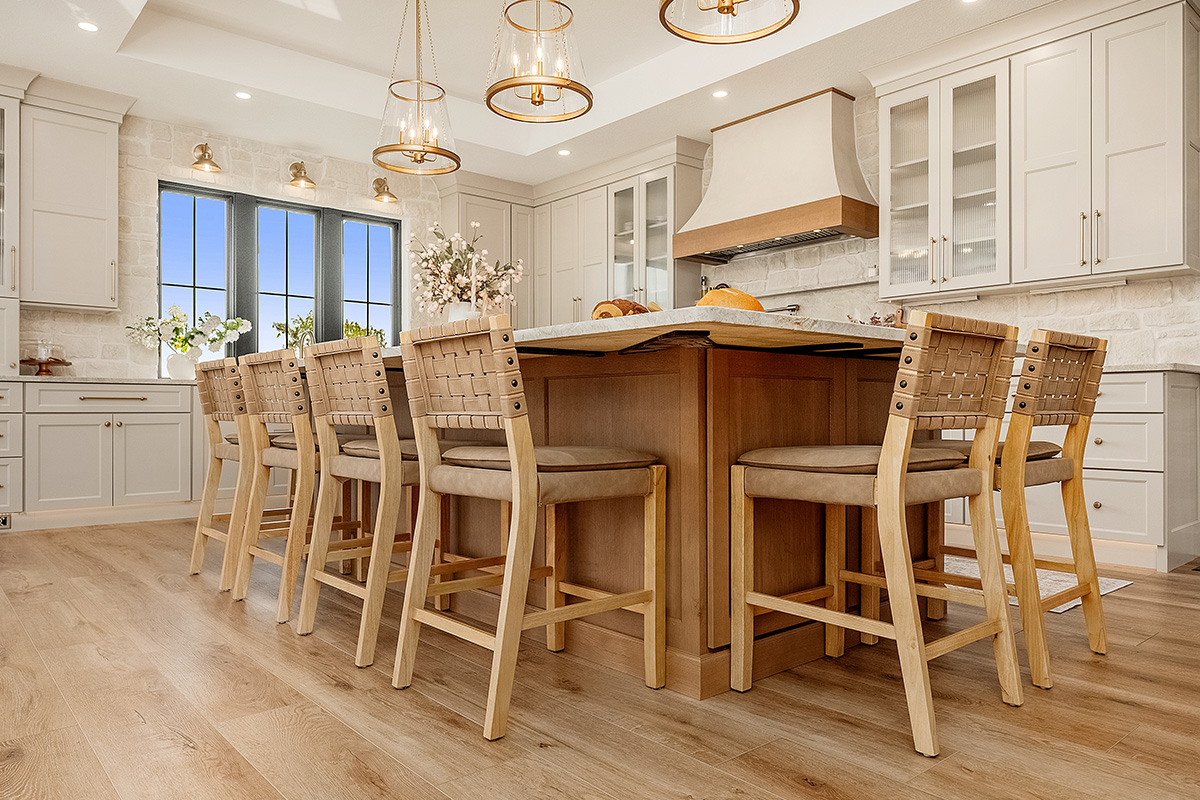 Painted and stained kitchen cabinets in a large open space with large windows.
