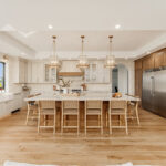 Painted and stained kitchen cabinets in a large open space with large windows.
