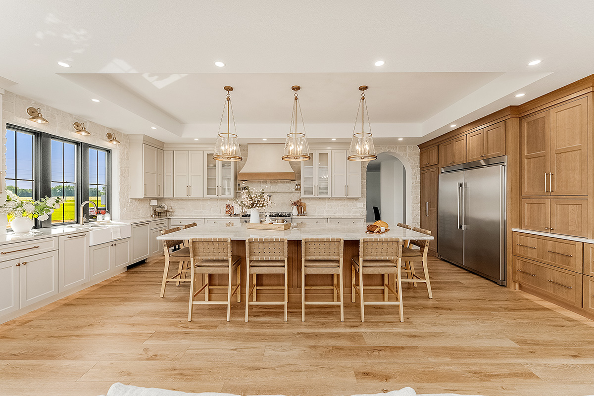 Painted and stained kitchen cabinets in a large open space with large windows.
