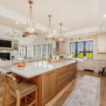 Painted and stained kitchen cabinets in a large open space with large windows.