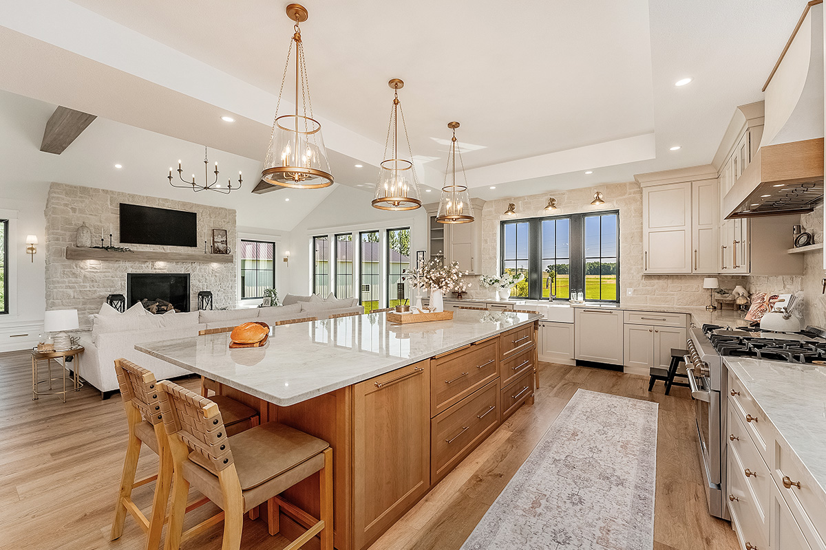 Painted and stained kitchen cabinets in a large open space with large windows.