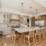 Painted and stained kitchen cabinets in a large open space with large windows.