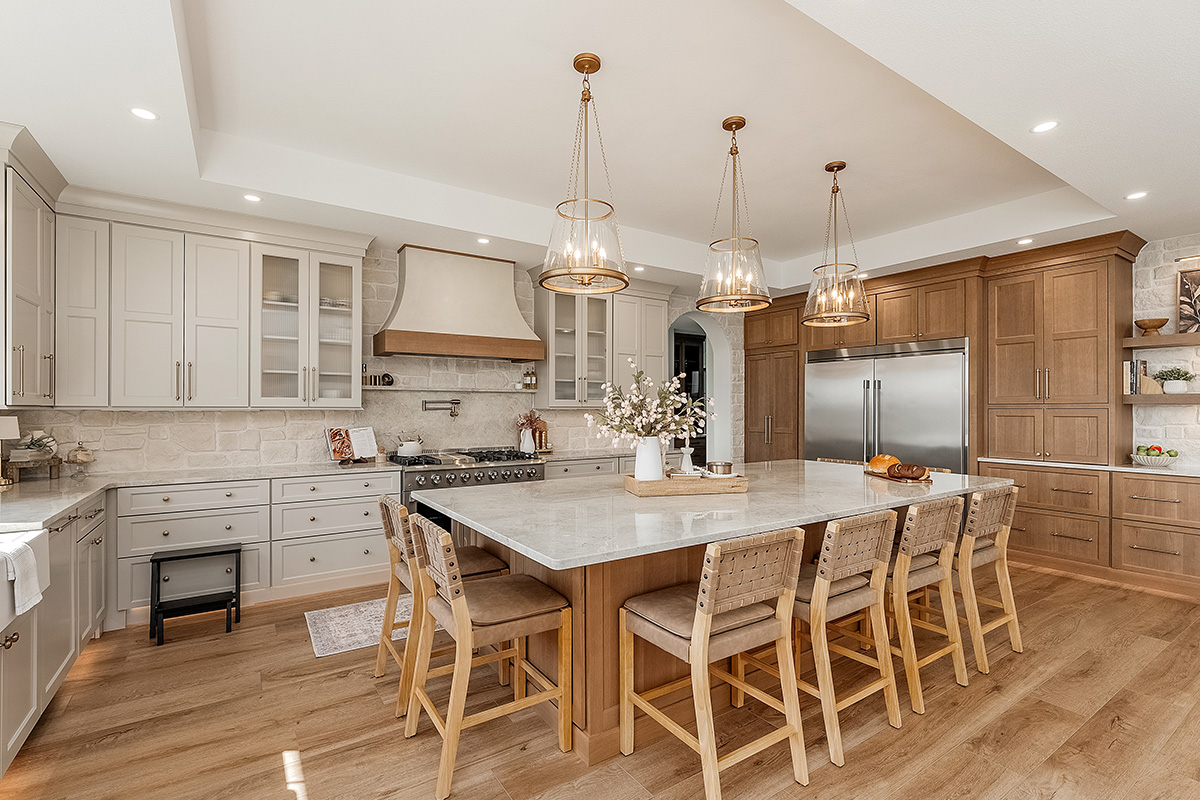 Painted and stained kitchen cabinets in a large open space with large windows.