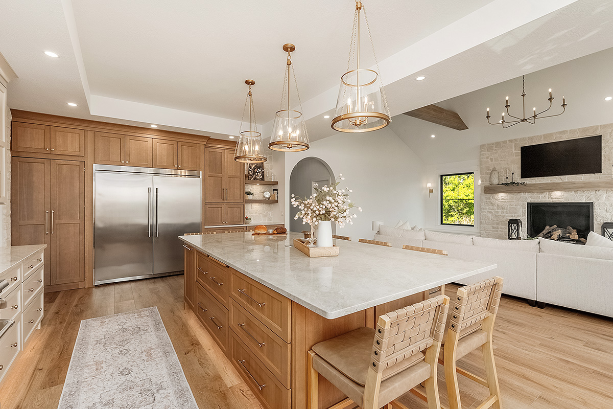 Painted and stained kitchen cabinets in a large open space with large windows.