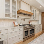 Painted and stained kitchen cabinets in a large open space with large windows.