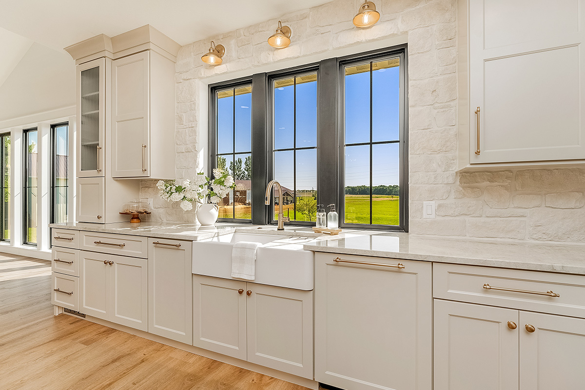Painted and stained kitchen cabinets in a large open space with large windows.
