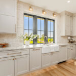 Painted and stained kitchen cabinets in a large open space with large windows.