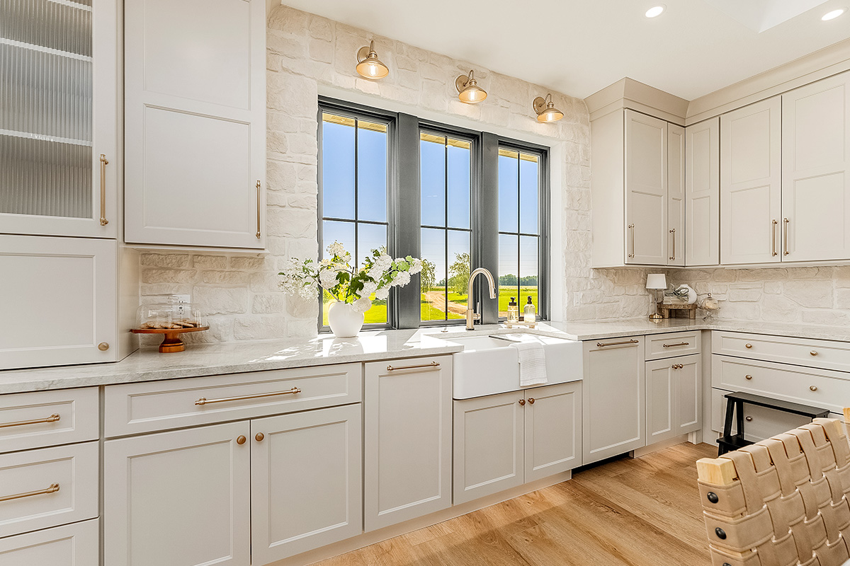 Painted and stained kitchen cabinets in a large open space with large windows.