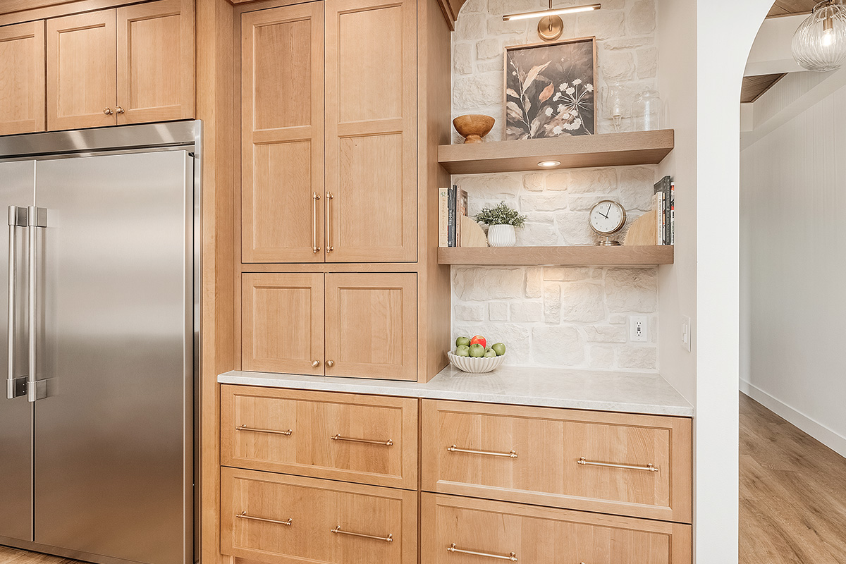 Painted and stained kitchen cabinets in a large open space with large windows.