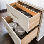White painted kitchen cabinets with drawers open showing plates