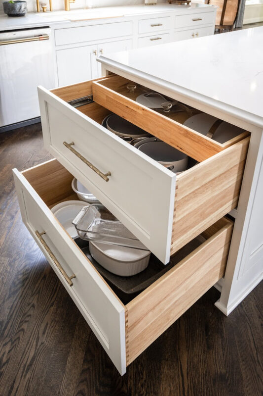 White painted kitchen cabinets with drawers open showing plates