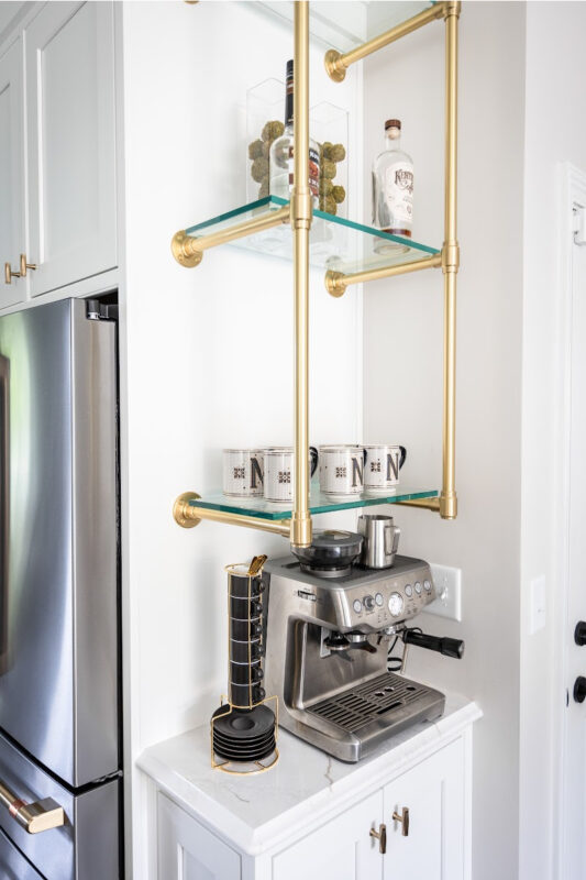 White painted coffee bar cabinets with gold shelf system above coffee maker.