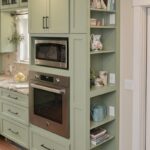 Painted kitchen cabinets in a mint green color. Showing a oven with microwave above in a cabinet with open shelving on the right side.