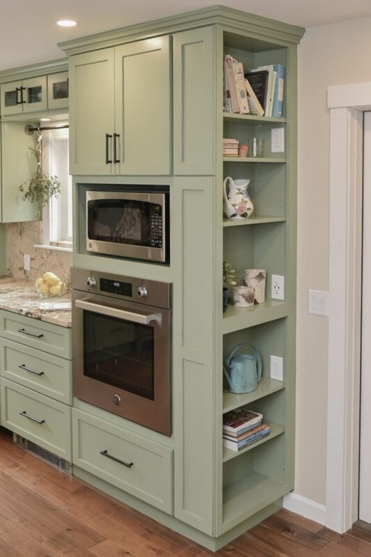 Painted kitchen cabinets in a mint green color. Showing a oven with microwave above in a cabinet with open shelving on the right side.