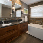 Floating vanity finished in Autumn stain near a large white tub.