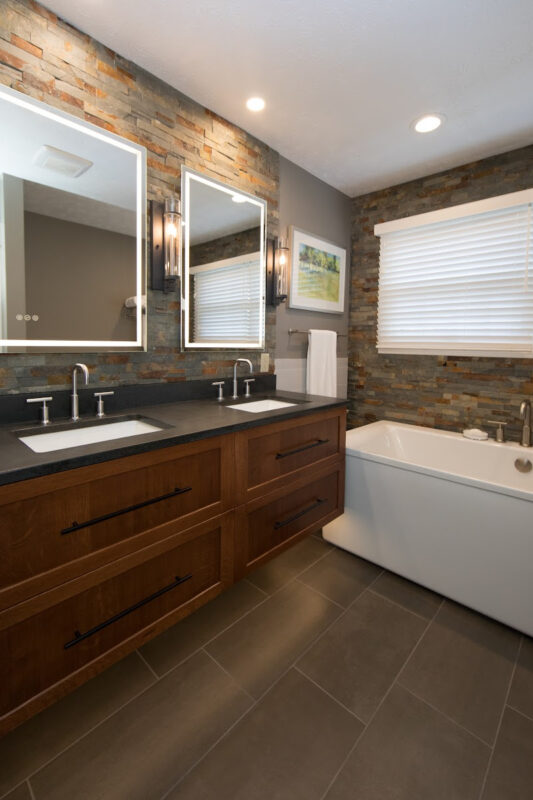 Floating vanity finished in Autumn stain near a large white tub.