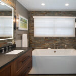 Floating vanity finished in Autumn stain near a large white tub.