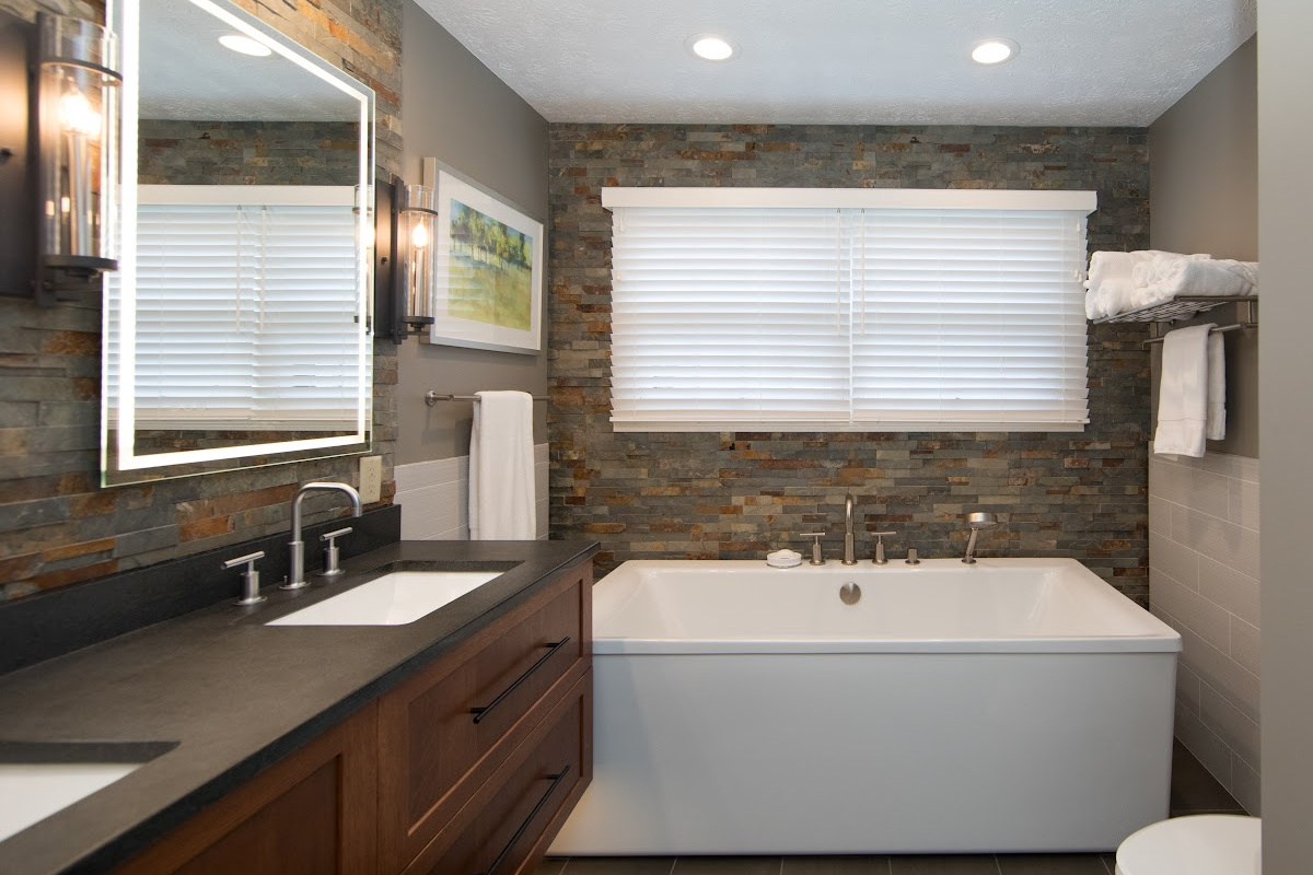 Floating vanity finished in Autumn stain near a large white tub.