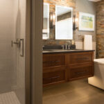 Floating vanity finished in Autumn stain near a large white tub.
