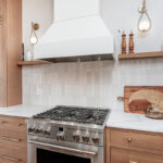Light brown-stained kitchen cabinets with a white painted wood hood