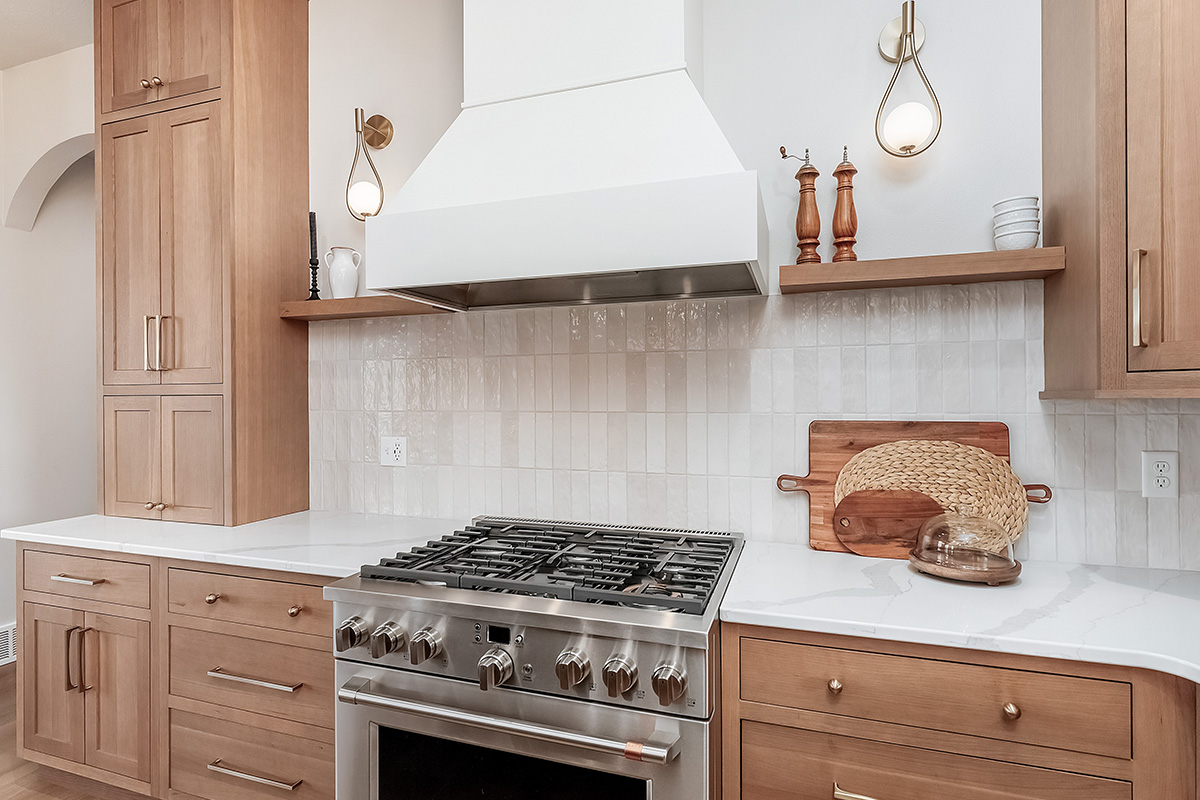 Light brown-stained kitchen cabinets with a white painted wood hood