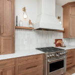 Light brown-stained kitchen cabinets with a white painted wood hood