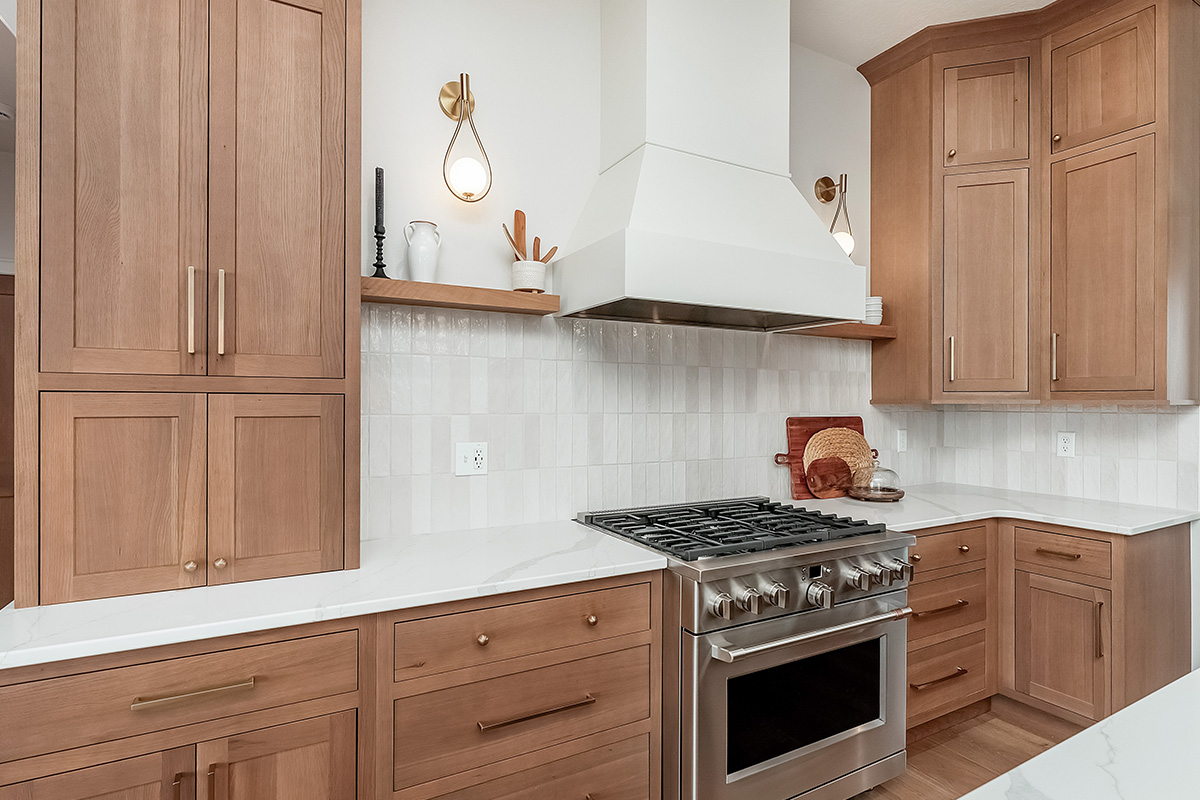 Light brown-stained kitchen cabinets with a white painted wood hood