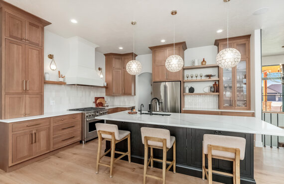 Light brown-stained kitchen cabinets with a white painted wood hood and dark stained island cabinets