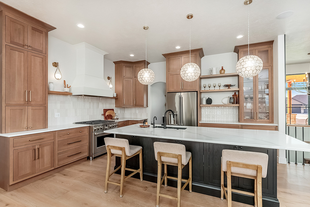 Light brown-stained kitchen cabinets with a white painted wood hood and dark stained island cabinets